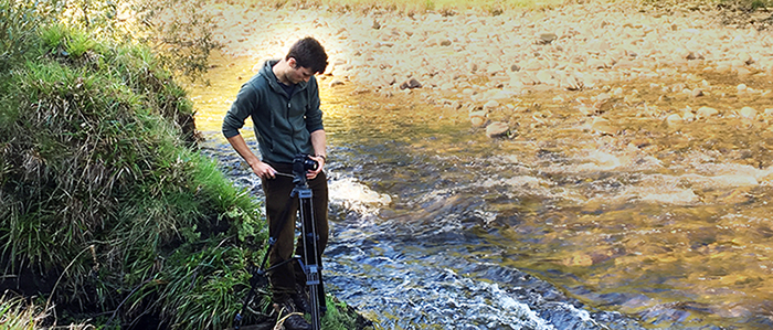 Photo of Jonathan with a tripod on a river bank